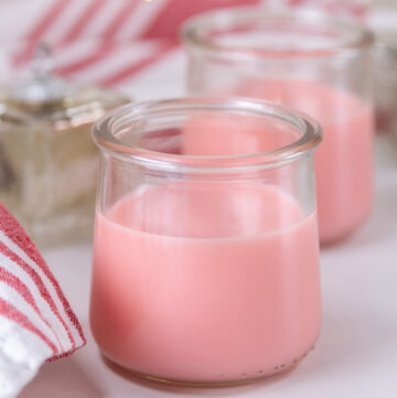 two glass jars filled with pink syrup.