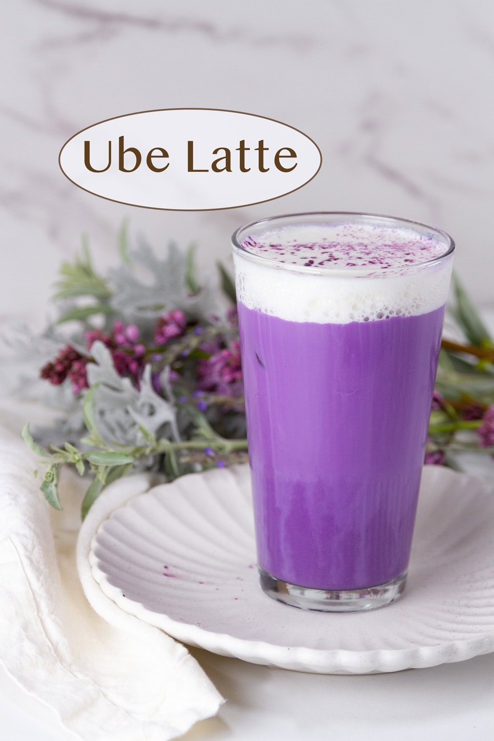 a bright purple drink topped with cold foam and flowers in the background.