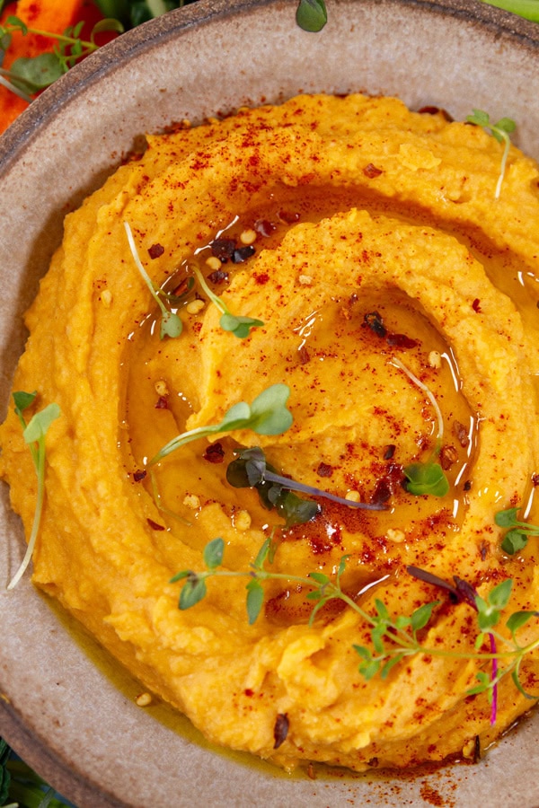 sweet potato hummus swirled with olive oil and garnished with sprouts and paprika.