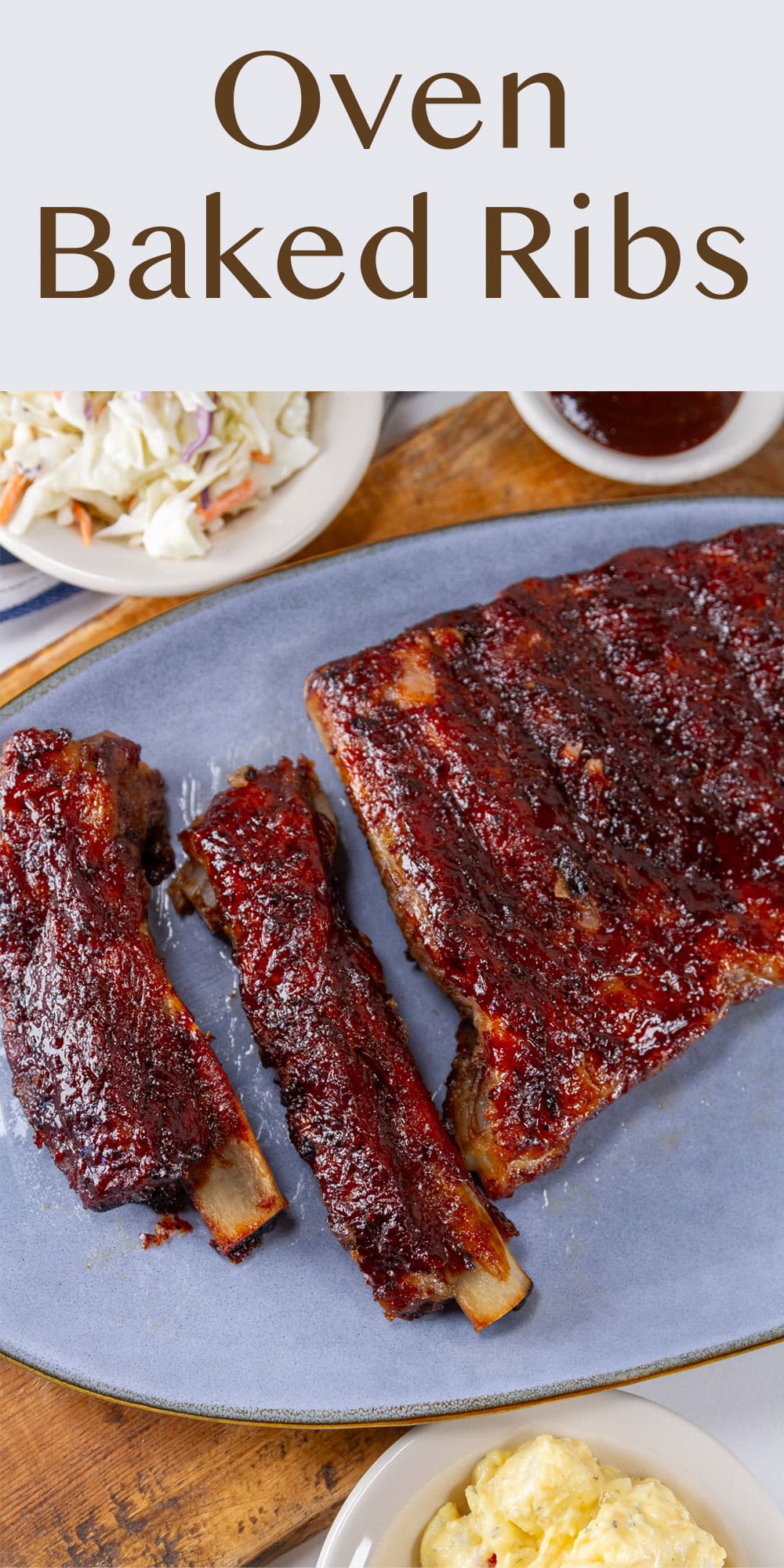oven baked ribs on a blue plate with side dishes next to it.