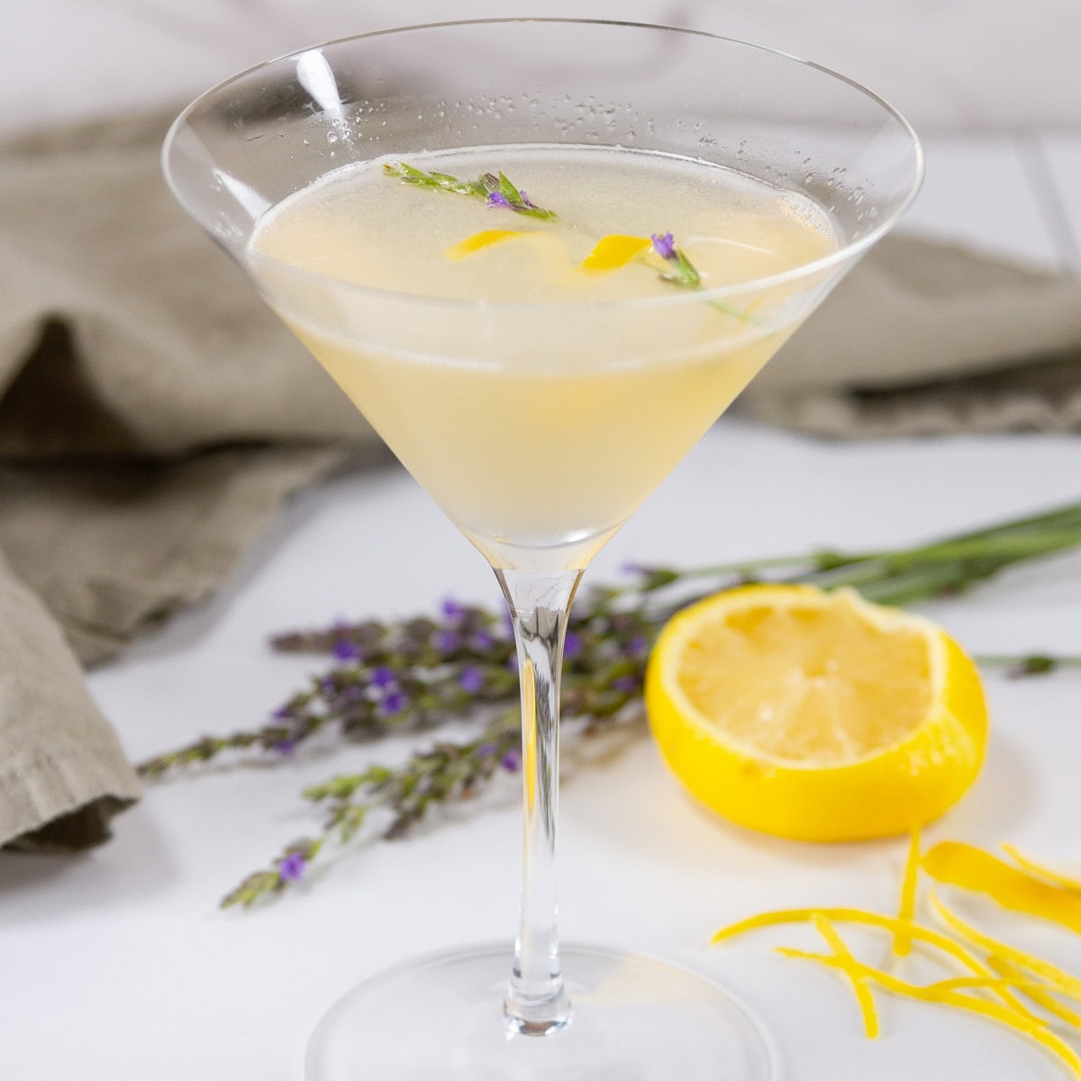square crop of a lemon drop martini with a green napkin and lemon wedge in the background.
