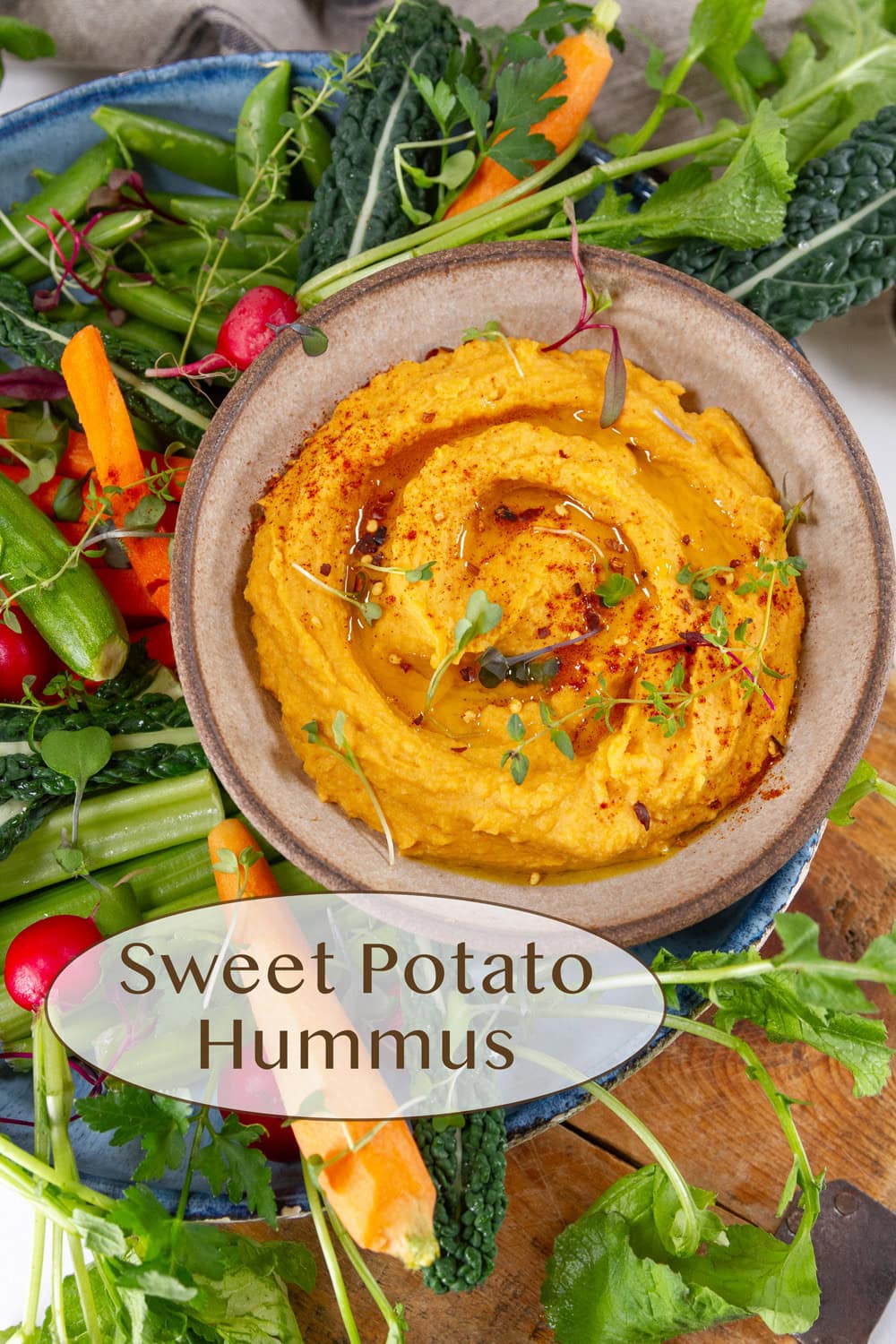 a bowl of sweet potato hummus surrounded by fresh veggies.