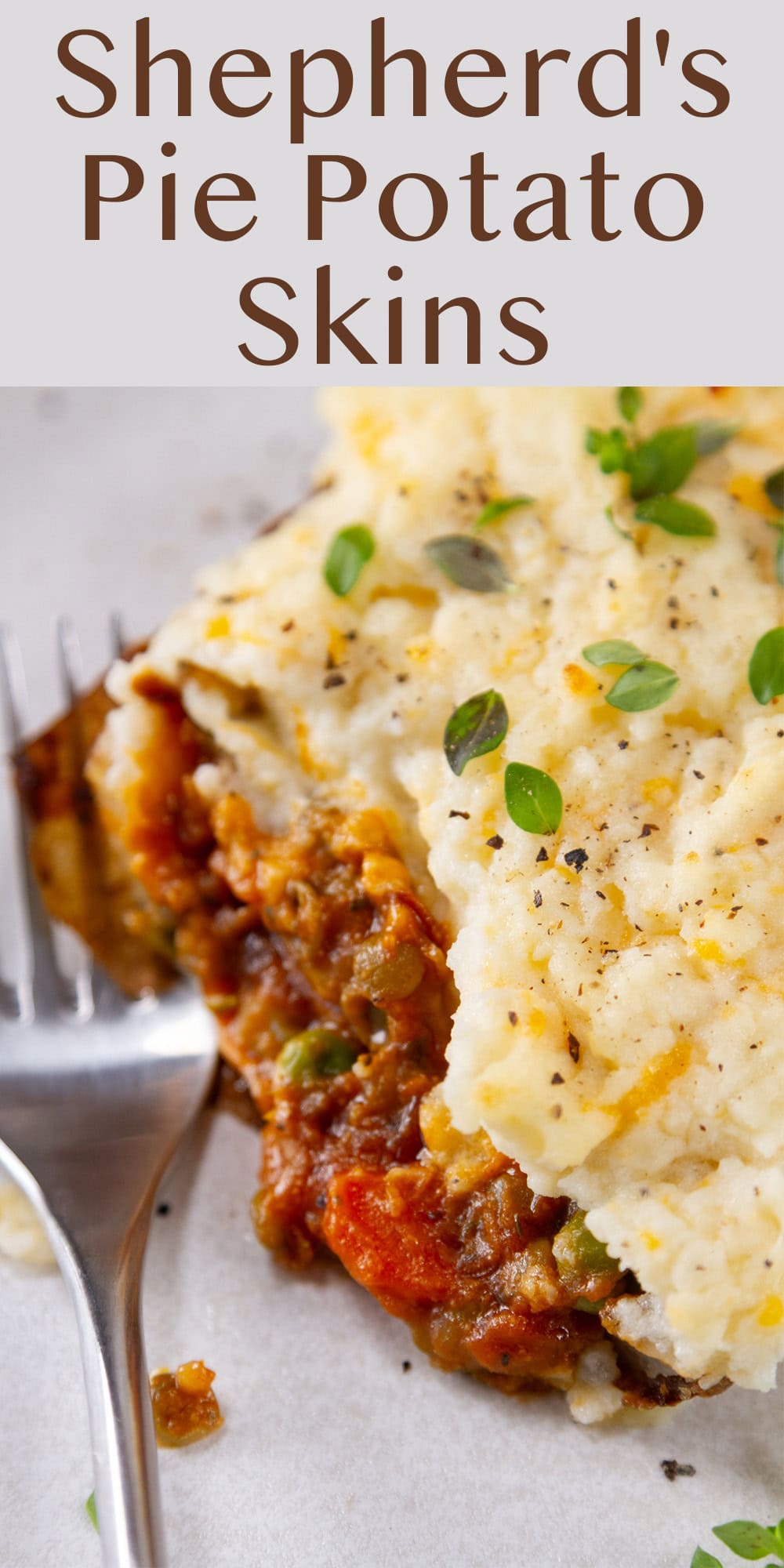 looking down onto a cut open potato skin filled Shepherd&rsquo;s Pie filling and topped with cheesy mashed potatoes, a fork to the left.