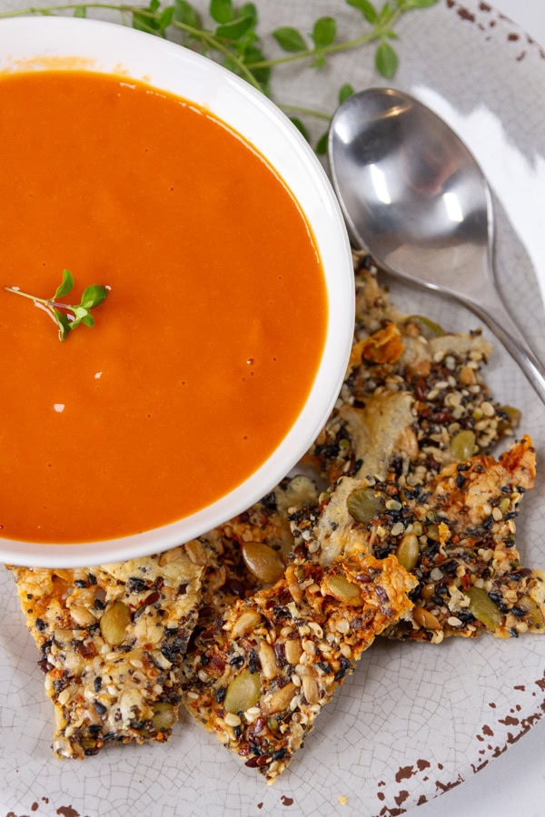 crackers next to a bowl of tomato soup.