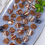 looking down on a blue platter with lots of mini cookies, some blueberries, and a sprig of mint on it.