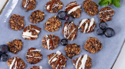 looking down on a blue platter with lots of mini cookies, some blueberries, and a sprig of mint on it.