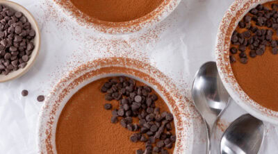 square crop of ramekins of tiramisu with some spoons around.