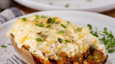 square crop of a cut open potato skin stuffed with shepherd's pie filling.