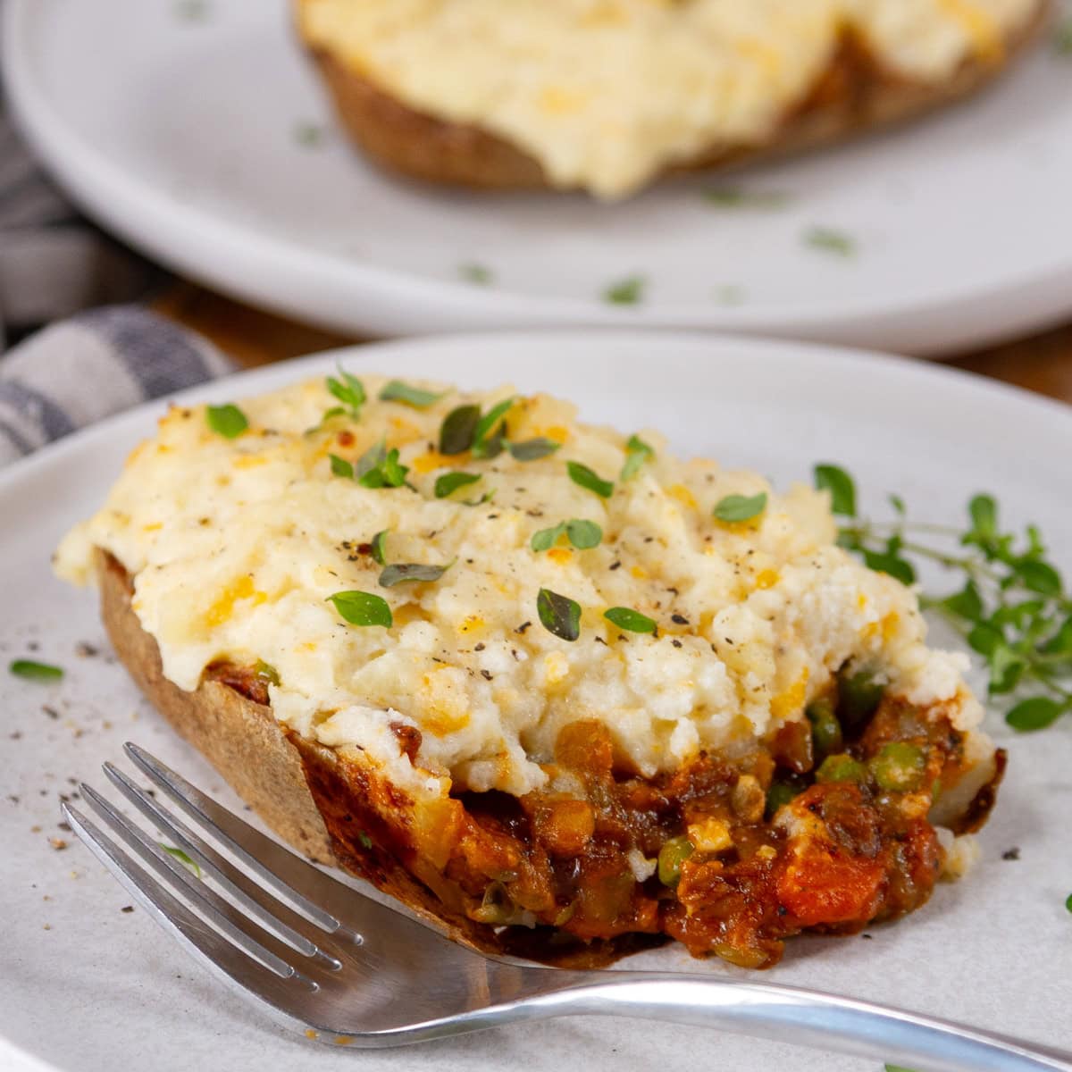 square crop of a cut open potato skin stuffed with shepherd's pie filling.