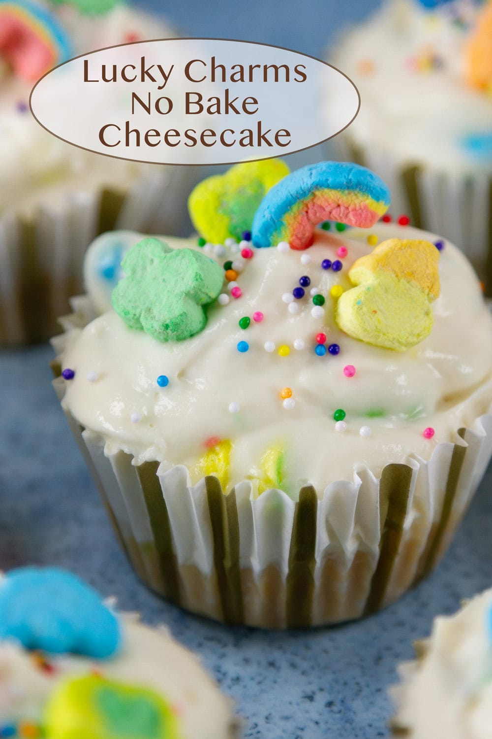 a cheesecake made in a paper cupcake liner topped with Lucky Charms marshmallows and rainbow sprinkles.