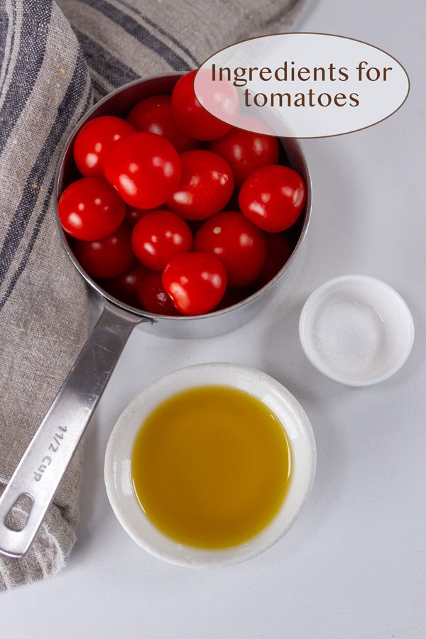 cherry tomatoes in a measuring cup with a small bowl of salt and oil.