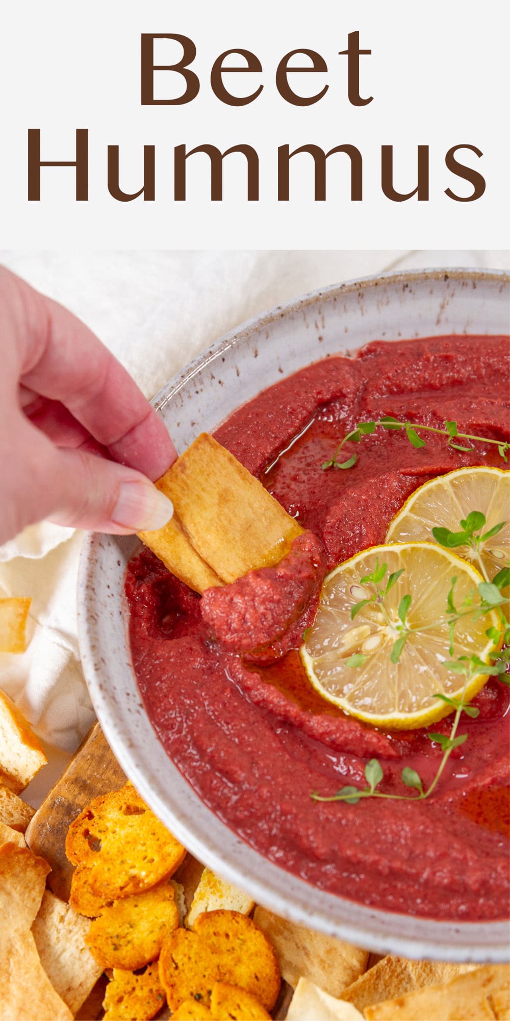 dipping a pita chip into hummus made with beetroot.
