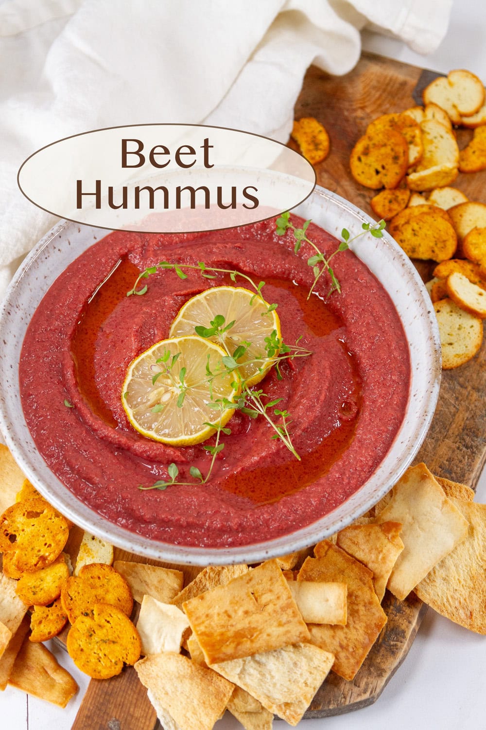 a white bowl filled with pink beet hummus and some chips around the outside.