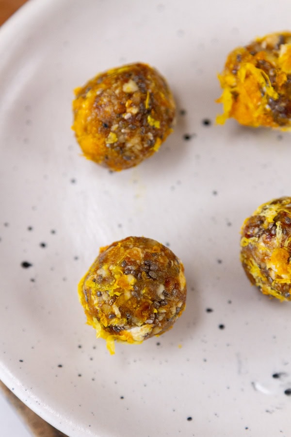 4 citrus energy bites on a white plate.