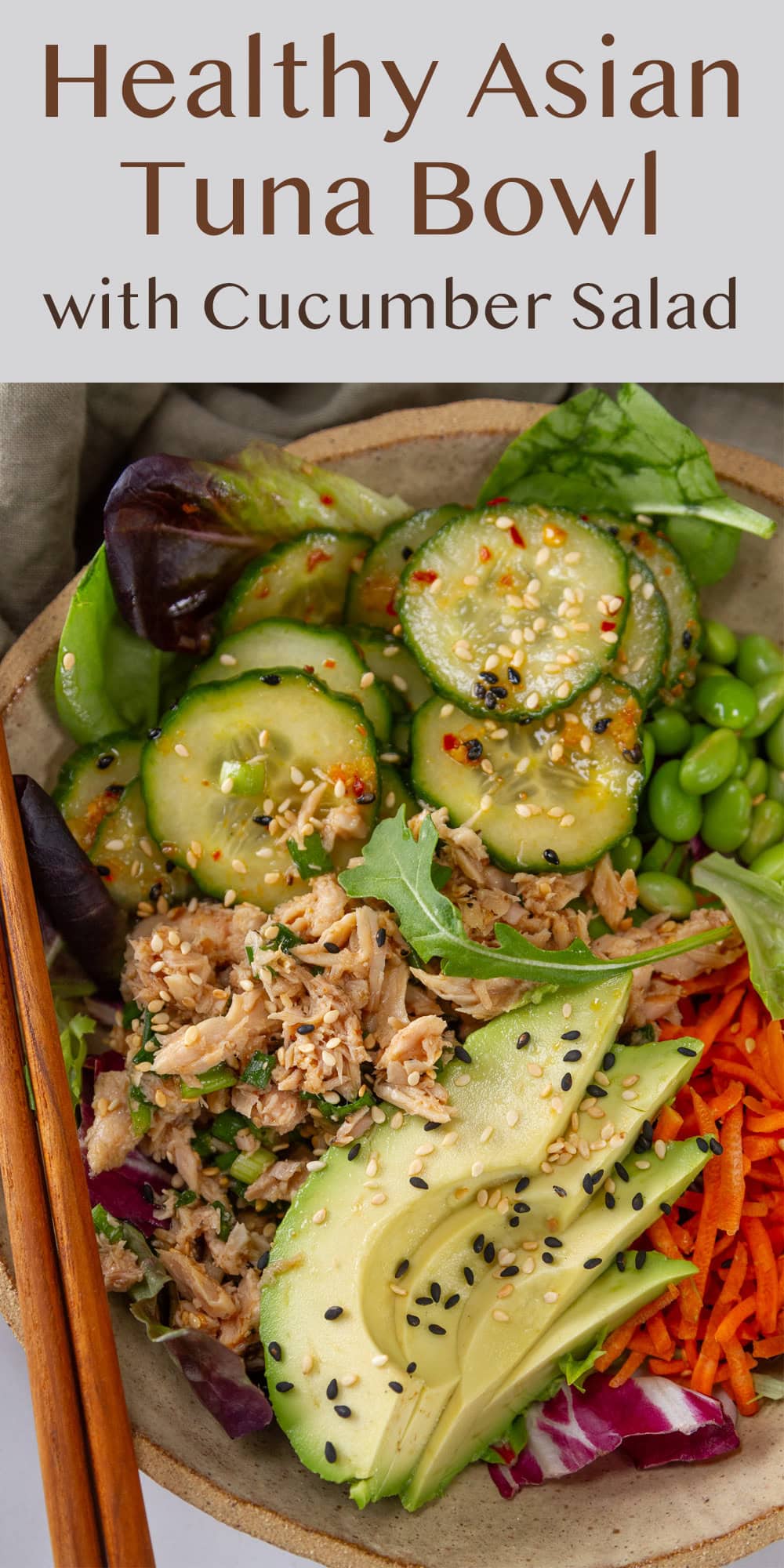 a bowl filled with cucumber salad, edamame, carrots, avocado, and tuna salad chopsticks to the left.