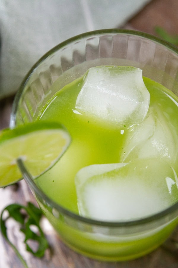 looking down into a glass filled with green mocktail drink over ice.