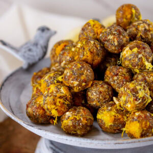square crop of lemon ginger energy bites on a metal serving tray.