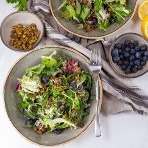 square crop looking down into bowls of salad with some of the salad makings around them.