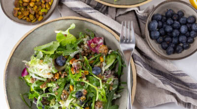 square crop looking down into bowls of salad with some of the salad makings around them.