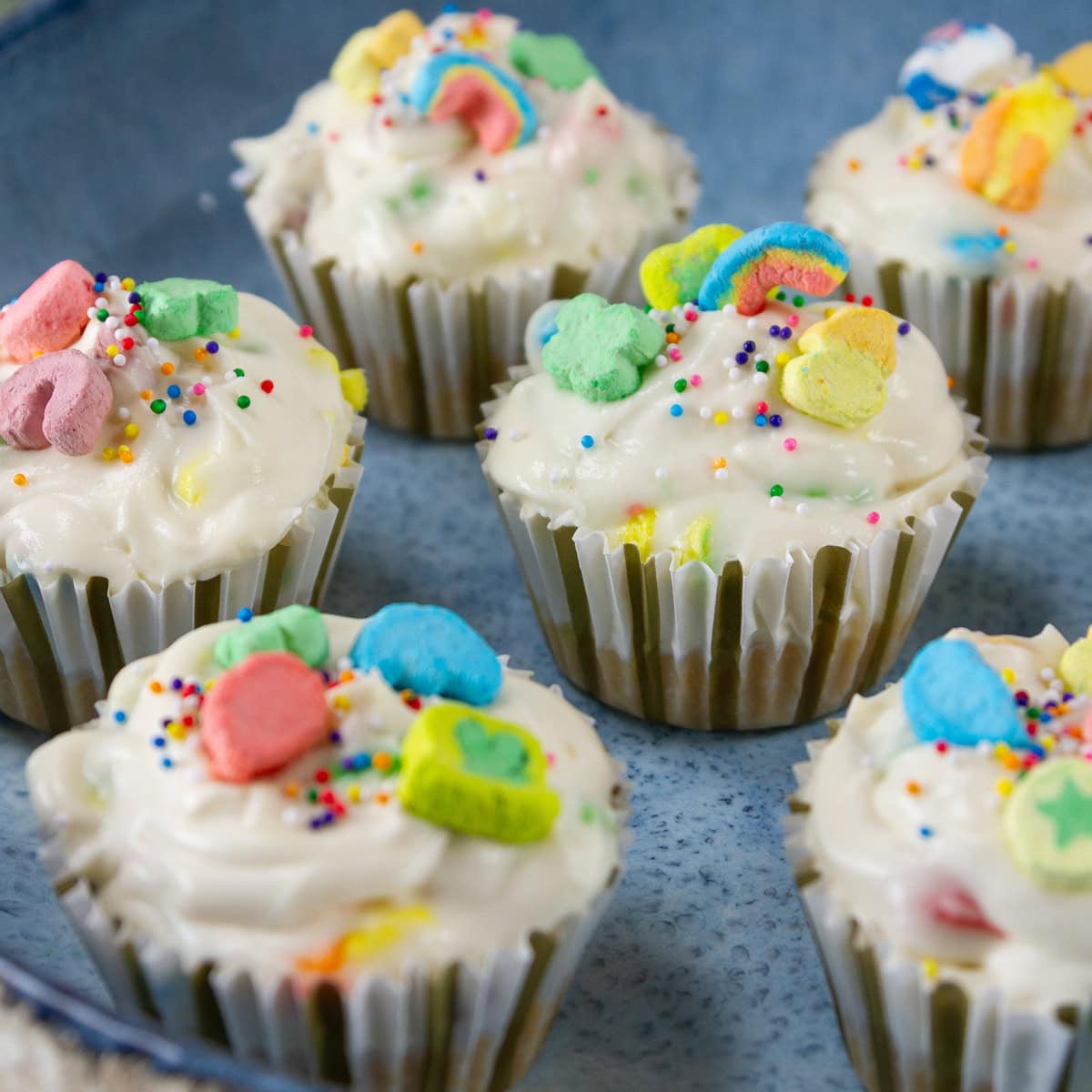 square crop of several individual cheesecakes on a blue serving platter.