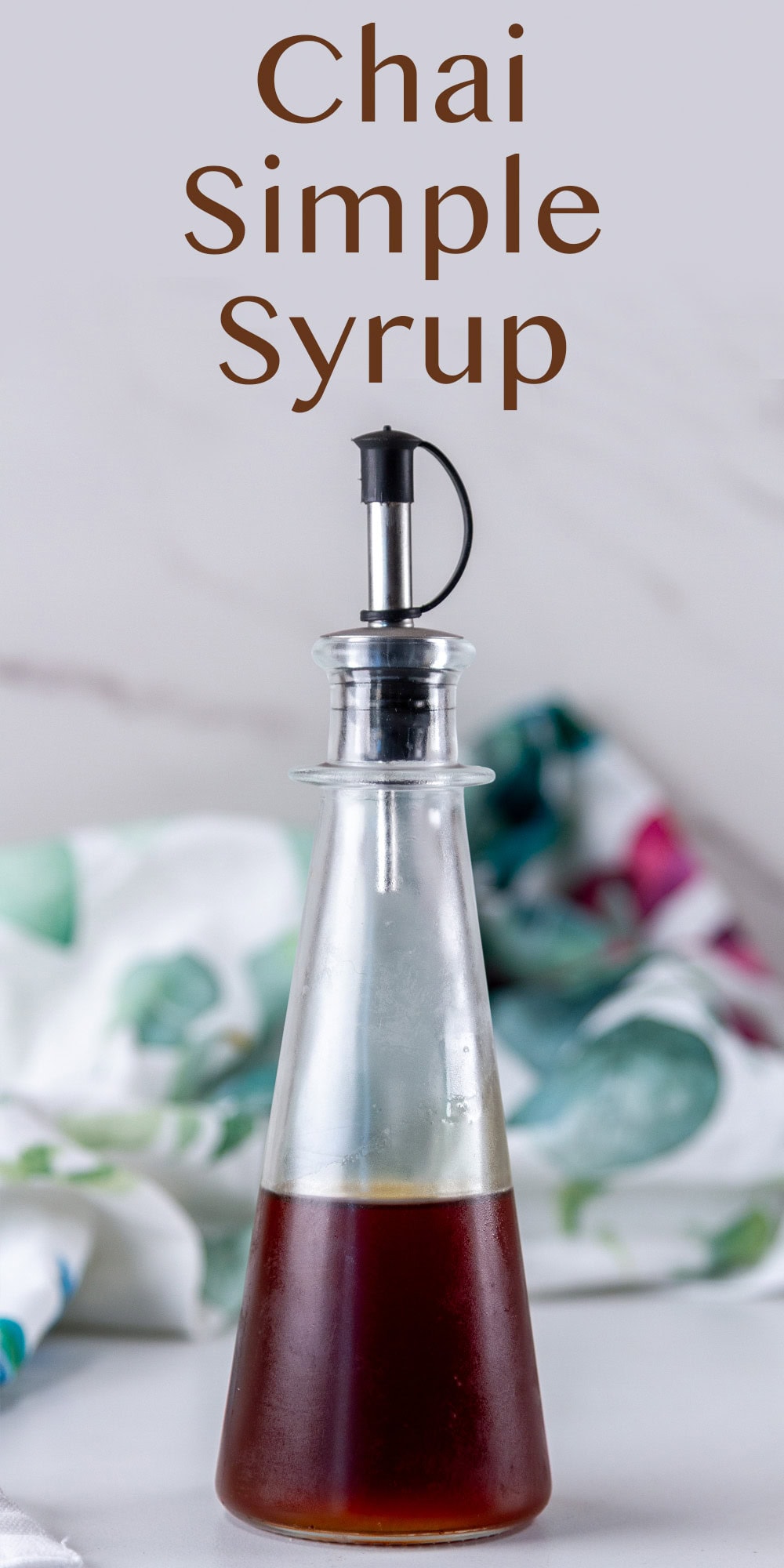 a pour bottle in front of a colorful towel.