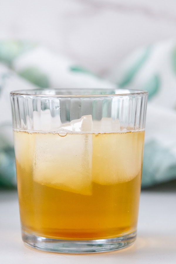 glass filled with ice and a drink in front of a colorful towel.