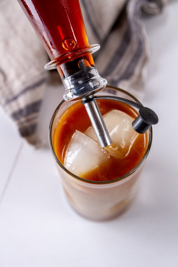 souring syrup into a glass with coffee and ice.