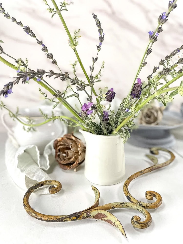 a small white pitcher with sage and lavender leaves in it.