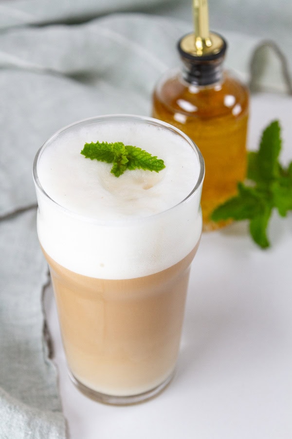 a mint latte in front of a jar of mint syrup.