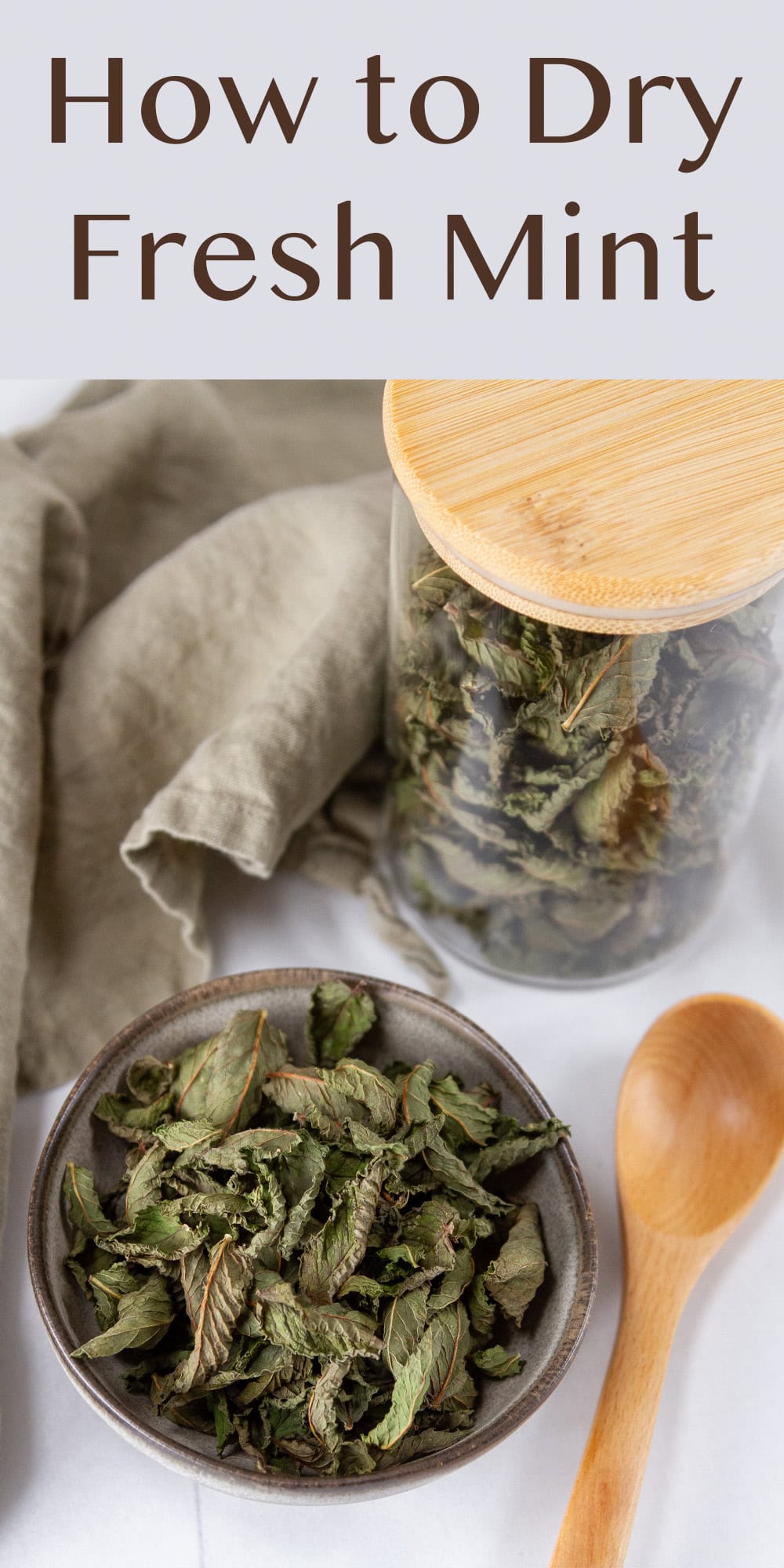 a small bowl of dried mint in front of a glass jar on the mint and a wooden spoon.