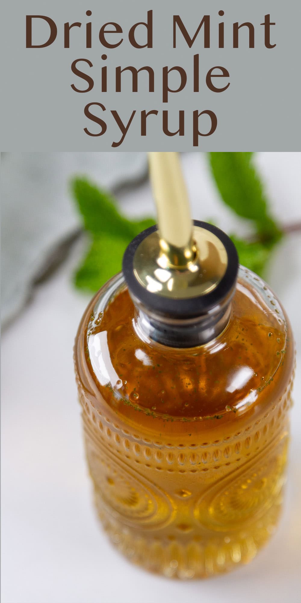 a glass bottle of simple syrup and some mint behind it.
