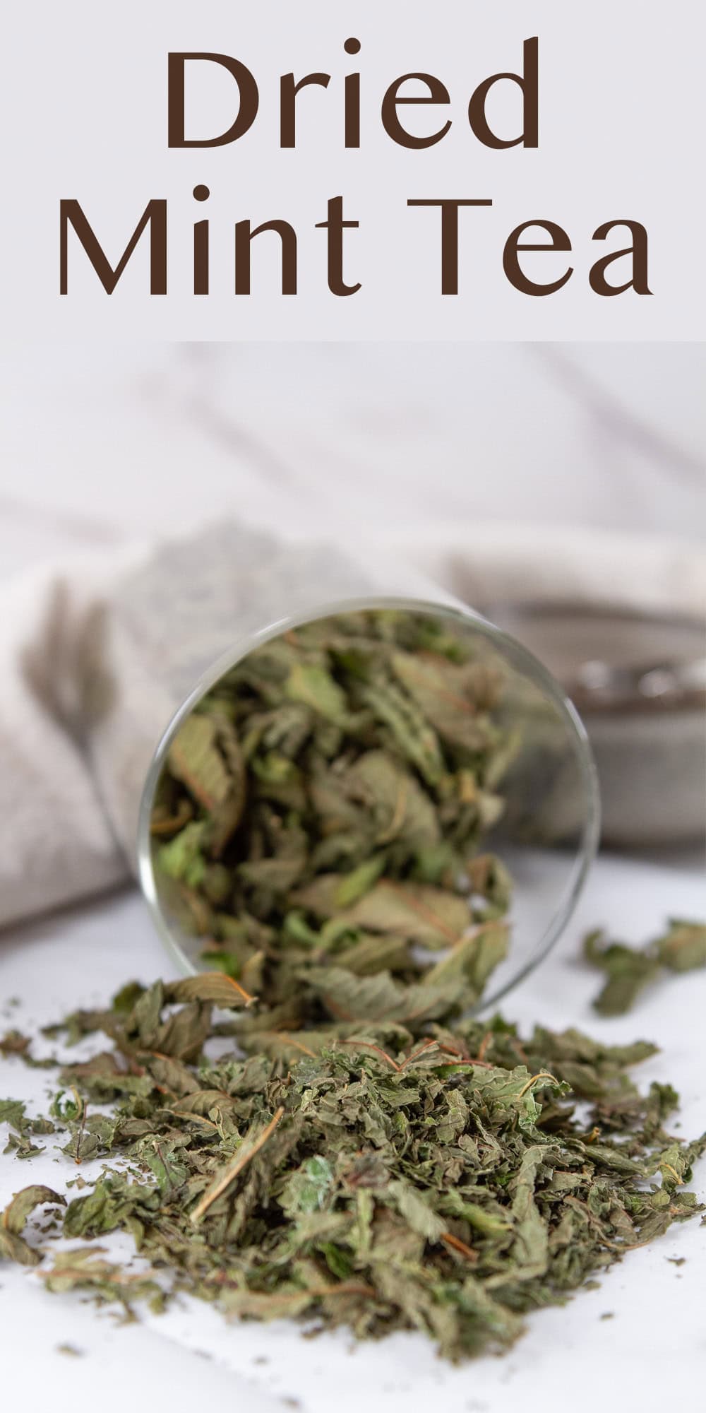 a glass canister of dried mint leaves spilled over so the leaves on on the counter.
