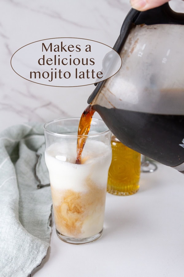 pouring coffee into a glass with milk and syrup.