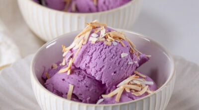 square crop of tow bowls of ube ice cream with toasted coconut and spoons.