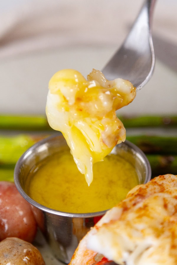 a piece of lobster dipped in butter sauce.