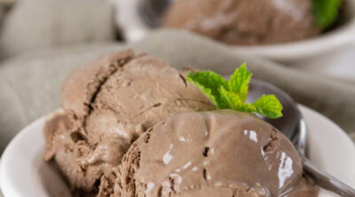 square crop of two dishes of ice cream garnished with fresh mint.