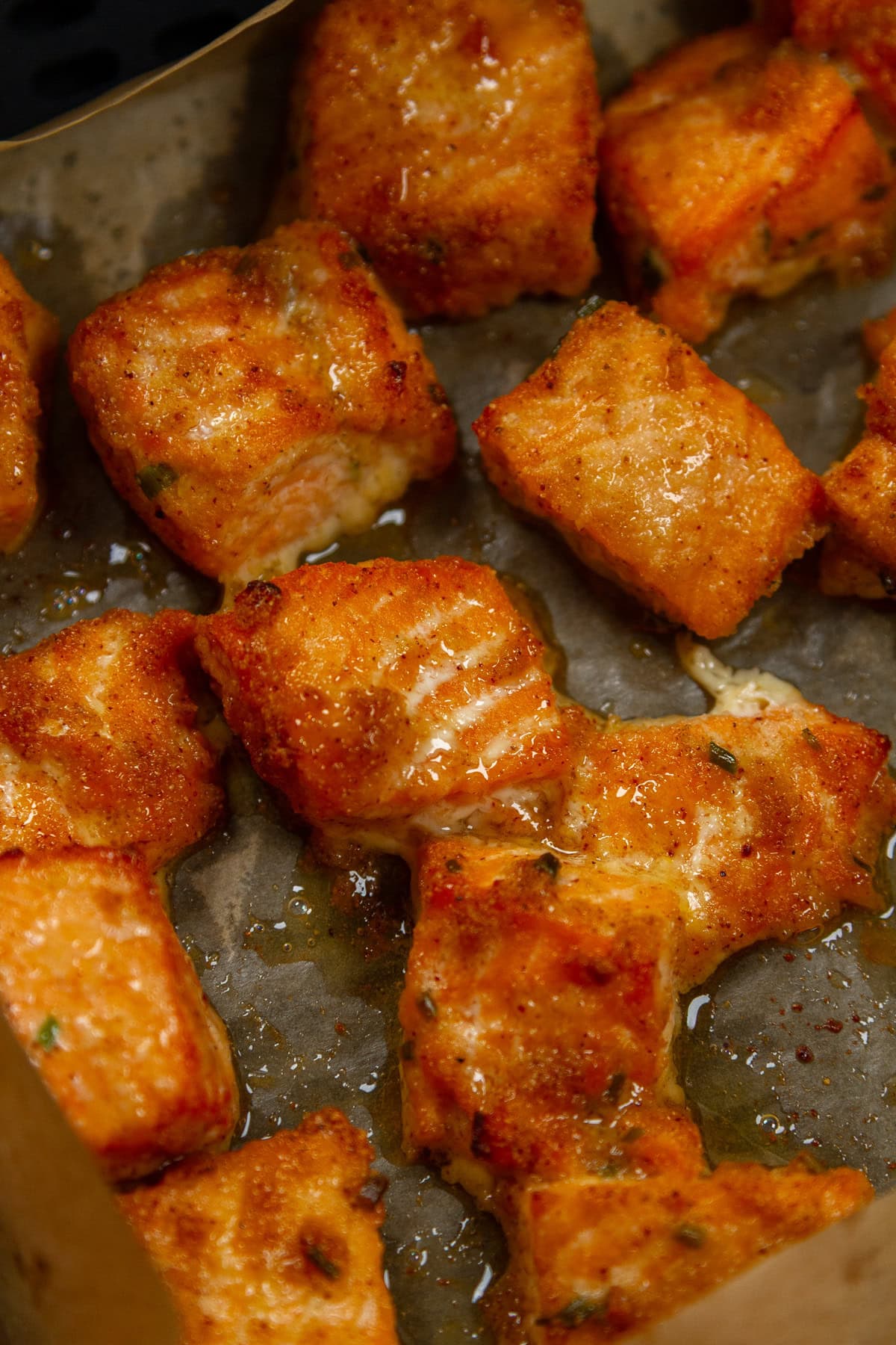cubes salmon cooked in an air fryer basket.