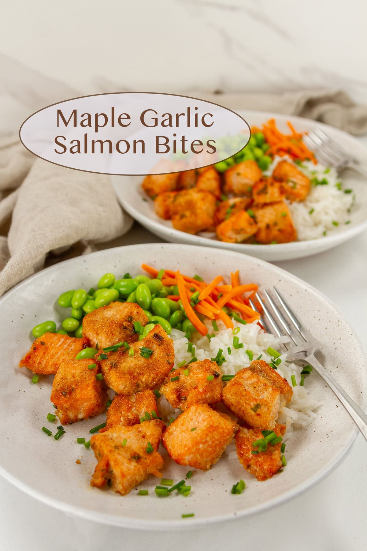 two bowls of maple garlic salmon bites served on rice with edamame and carrots.