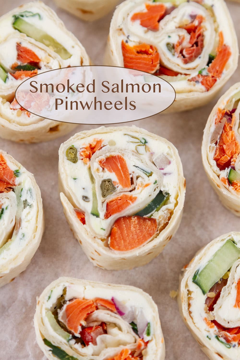 smoked salmon pinwheels served as appetizers on a wooden board with parchment paper.