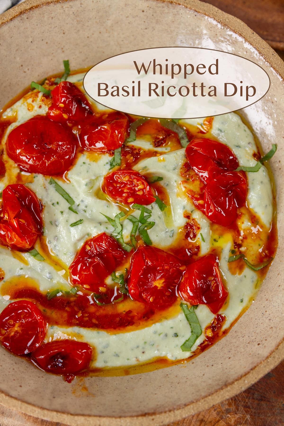 a bowl of whipped ricotta with roasted tomatoes, chili garlic sauce, and basil.