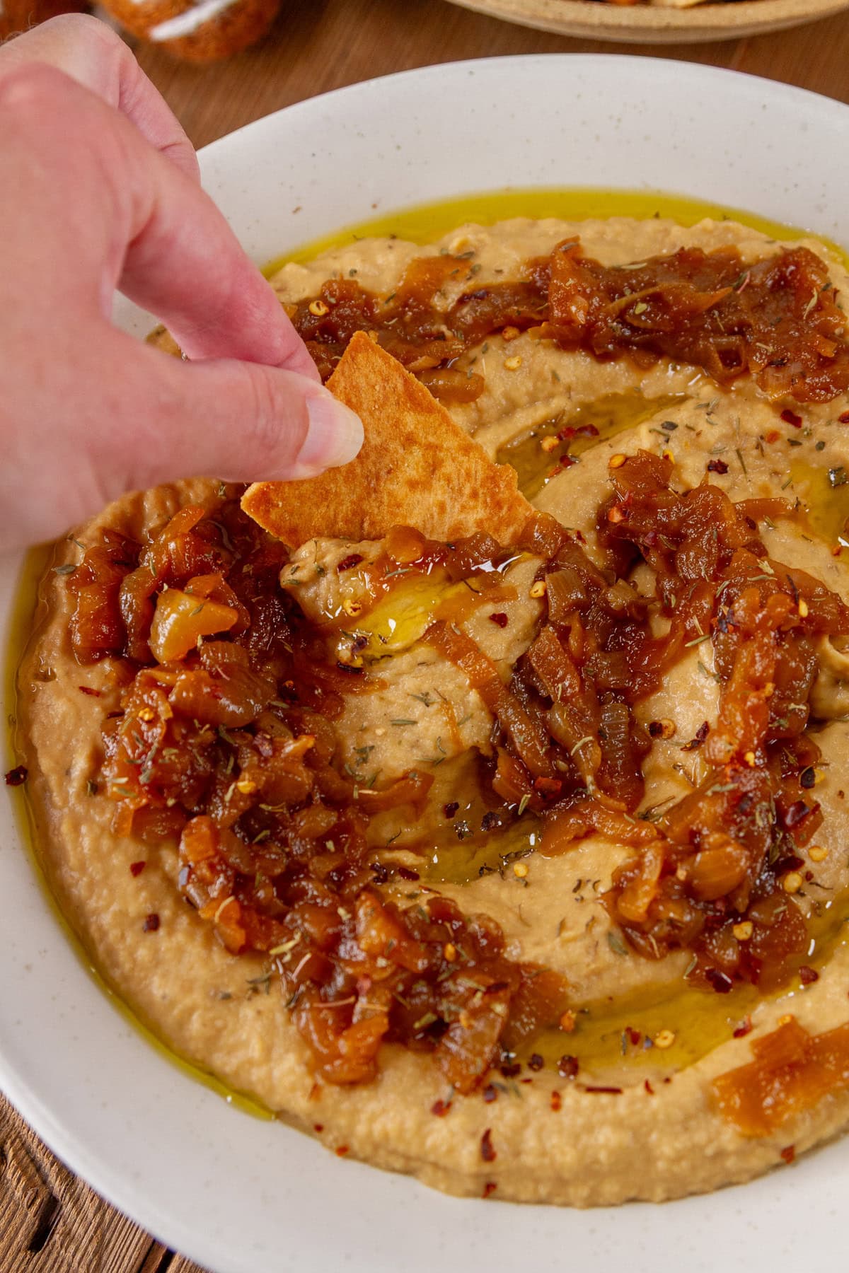 scooping up hummus dip with a pita chip.