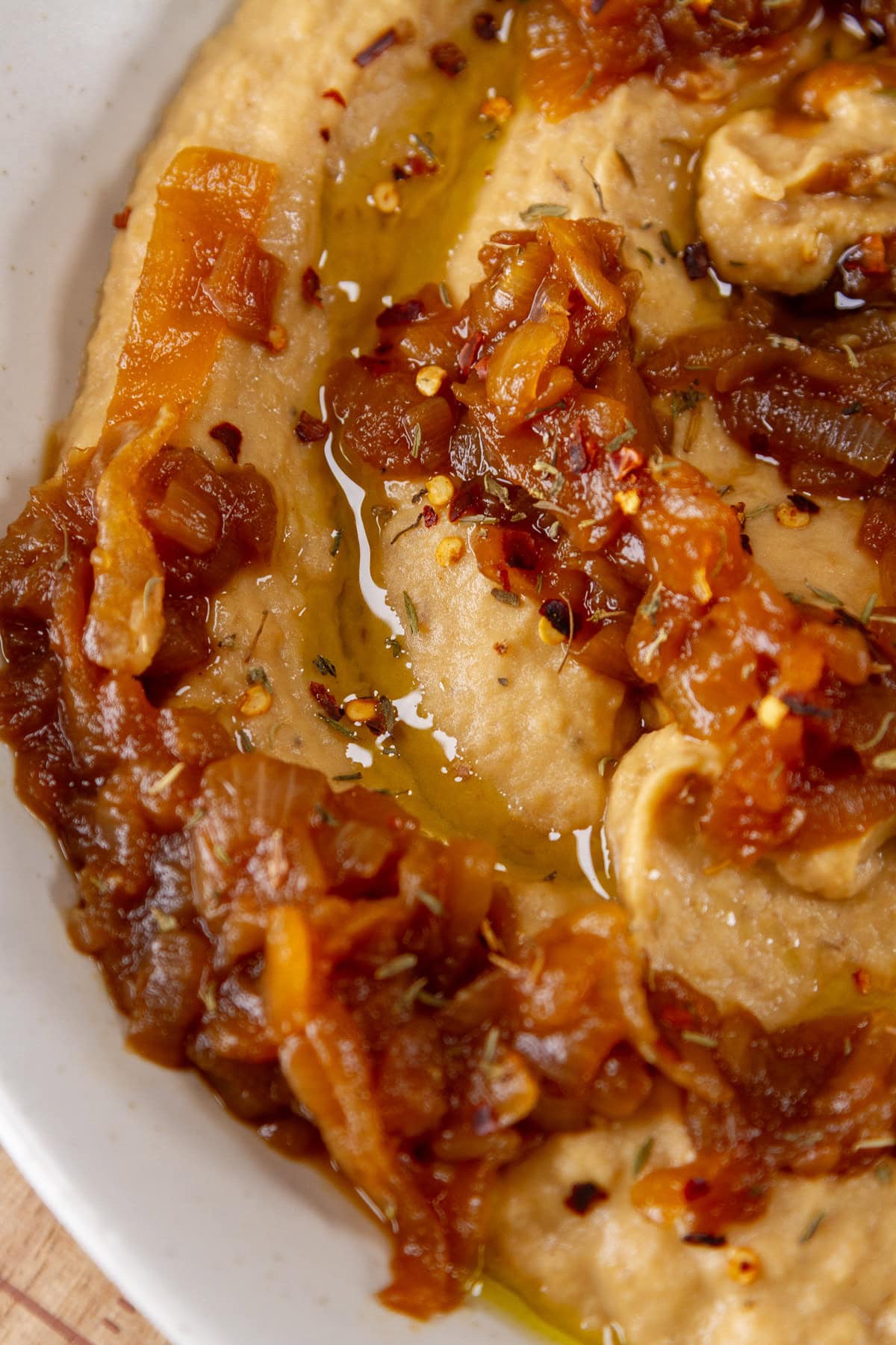 close up on hummus in a bowl with caramelized onions.