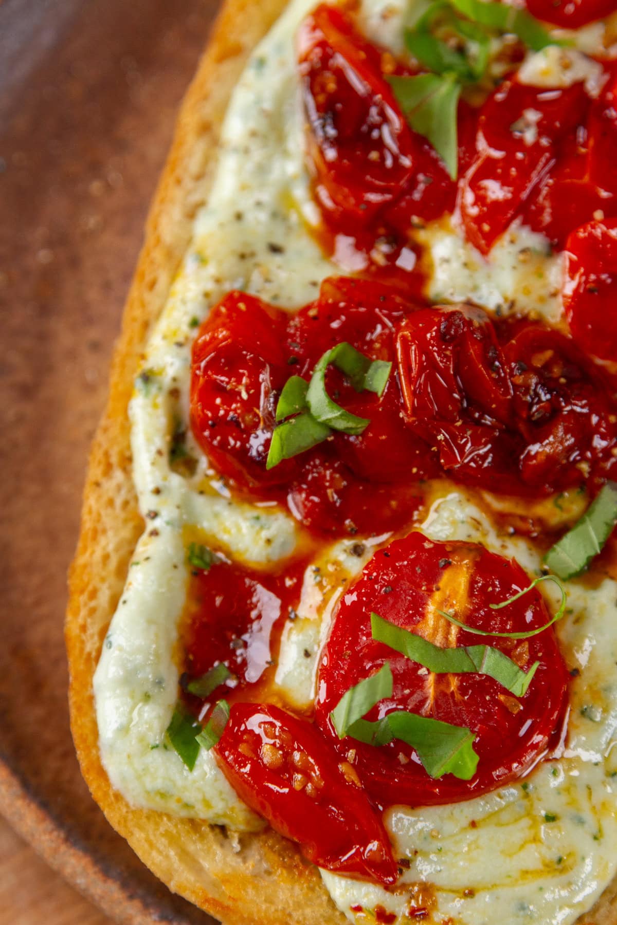 close up on ricotta toast topped with cherry tomatoes and basil.