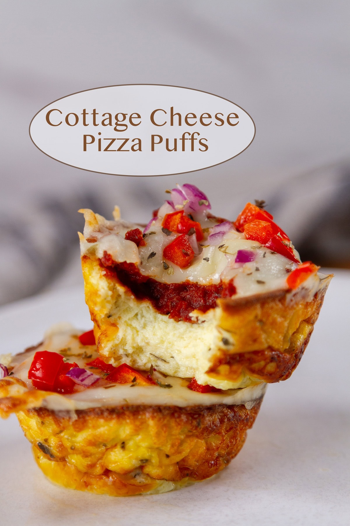 two pizza puffs stacked on top of each other, the one on top has a bite taken out of it.