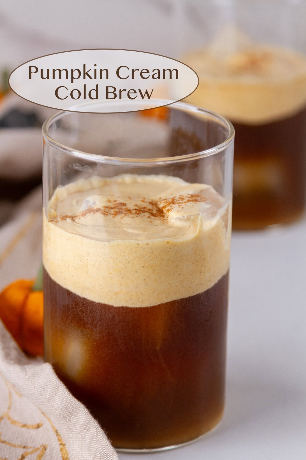 two glasses of Pumpkin Cream Cold Brew with some fall decorations around. 