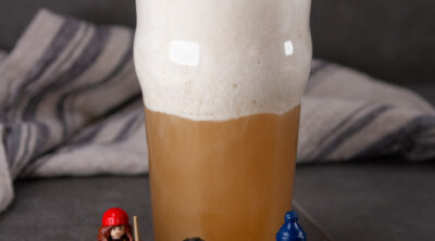 square crop of a glass of butterbeer with Lego Harry Potter figures around it.