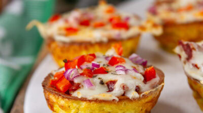 square crop of pizza puffs on a white tray in front of football props.