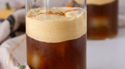 square crop of two glasses of iced coffee with pumpkin cold foam on top.