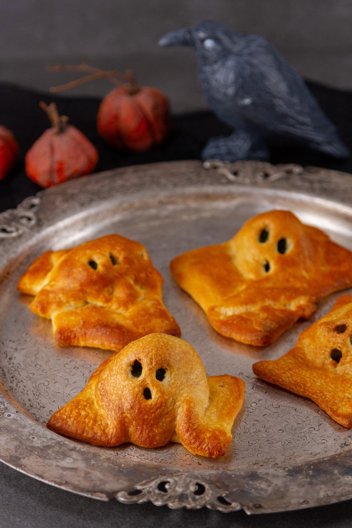 crescent roll dough shaped like ghosts on a pewter platter.
