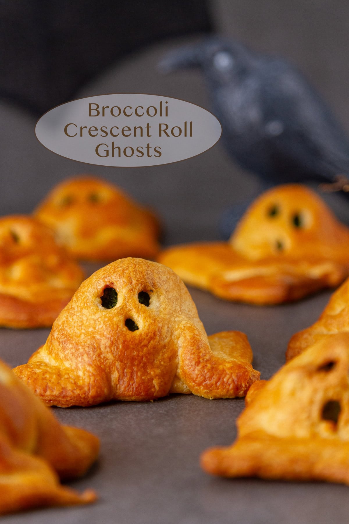 crescent roll ghosts on a black background with a Halloween crow in the back.